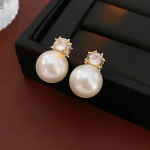 Macro detail of elegant pearl earrings with square zirconia in gold claw setting