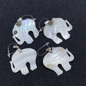 Macro shot of four elephant-shaped white mother of pearl pendants with silver clasps
