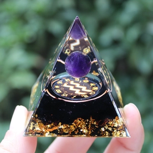 Detailed close-up of Orgone pyramid with purple crystal sphere and Aquarius zodiac symbol
