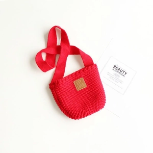 Dettaglio macro della borsa a tracolla in maglia rossa con etichetta in pelle EST LOVE