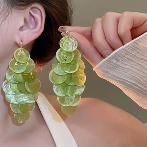 Macro detail of green shell tassel earrings featuring translucent circular layered discs