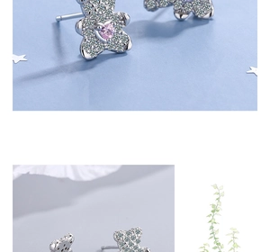 Detailed view of silver bear earrings with white zircon paving and pink heart stone