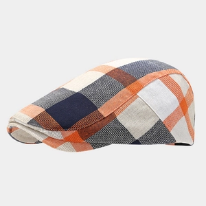 Detail view of British style plaid newsboy cap with orange and navy checkered texture