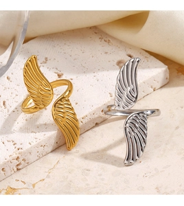 Detailed view of adjustable gold and silver wing rings on white travertine stone base