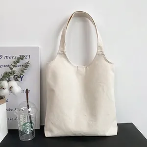Detail of minimalist beige canvas tote bag with wide shoulder straps on a display stand