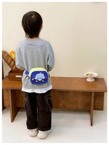 Boy wearing a cartoon police car waist bag with adjustable yellow straps in a lifestyle setting