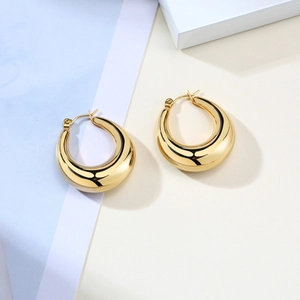 Detailed view of chunky golden water drop earrings with polished metallic surface