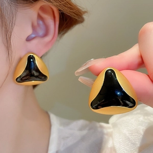 Vintage gold-trimmed black triangle stud earrings shown on model and in close-up detail