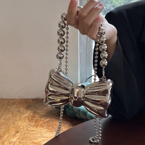 Dettaglio della borsa a fiocco in metallo argento con finitura a specchio e tracolla a sfere