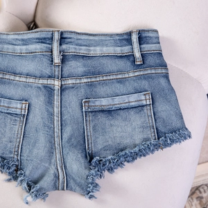 Dettaglio degli shorts in denim con orli sfilacciati e cuciture blu classiche
