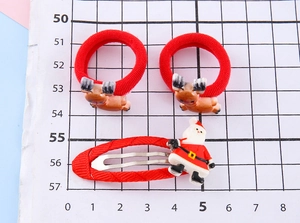 Detailed view of red reindeer antler hair ties and Santa clip on a measurement grid scale