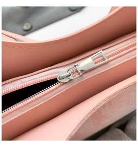 Close-up of pink leather bucket bag showing silver metal zipper detail and texture