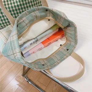 Detailed interior view of green checkered tote bag showing zipper and spacious lining