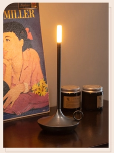 Portable LED table lamp with handle and warm light on a dark wooden surface in cozy setup