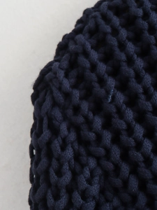 Detailed macro shot of dark blue chunky fish-scale knit fabric showing thick texture
