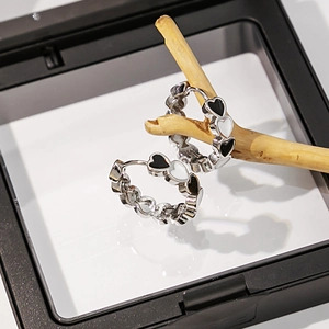Détail de boucles d'oreilles cœur argentées aux motifs noirs et blancs sur bois