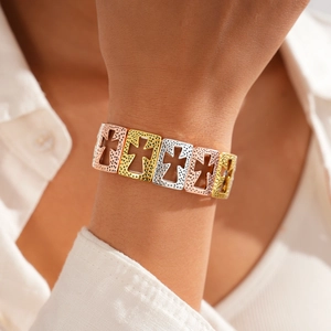 Detail of tricolor hollow cross metal bracelet with hammered texture on wrist