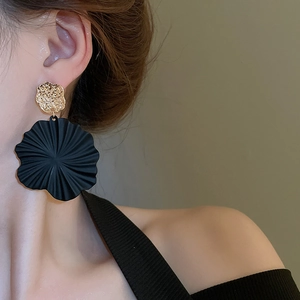 Detailaufnahme der Vintage-Ohrringe mit schwarzen Spiralblumen und gehämmerter Goldoptik