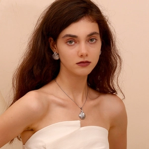 Silver shell necklace and earring set shown on a model with warm soft lighting