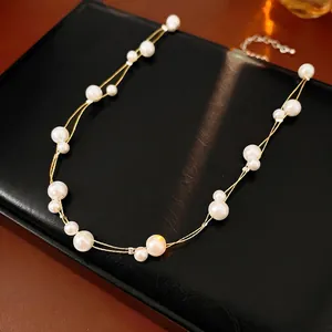 Collier élégant à double chaîne dorée avec perles sur fond texturé noir raffiné