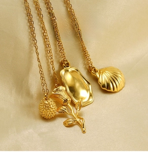 Détail de quatre pendentifs dorés en acier inoxydable sur soie avec formes rose et coquillage
