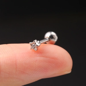 Detailed close-up of a tiny silver star cartilage stud earring with a central zircon gem