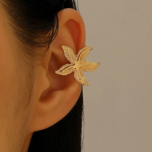 Macro view of a golden starfish ear cuff earring worn on the cartilage of the ear