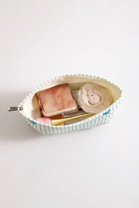 Detail of white striped canvas cosmetic bag with blue dragonfly embroidery and brushes