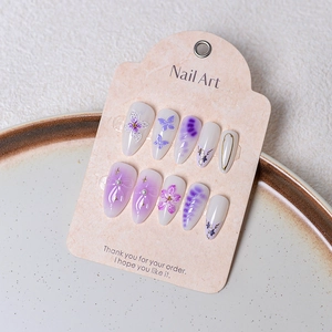 Detail view of handmade French almond press-on nails with 3D purple flowers and pearls