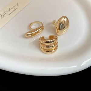 Detailed view of three minimalist gold polished rings with bean and layered designs