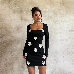 Vue détaillée des fleurs 3D blanches sur une robe mini noire à manches longues