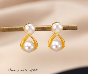 Macro detail of S925 silver cross pearl earrings with infinity design on silk background