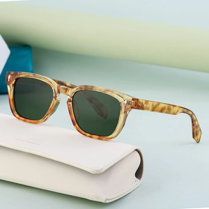 Polarized cat-eye sunglasses with tortoise frame and dark green lenses on case