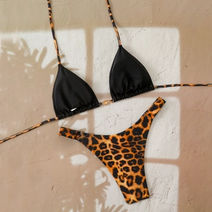 Detailed flat lay of leopard bikini with golden sun buckle and sunlight shadows