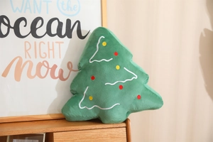 Detailed view of green plush Christmas tree pillow with red and yellow polka dots decoration
