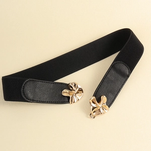 Elastic wide black belt for women featuring gold floral metal buckle on beige background