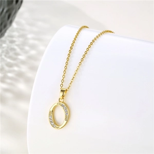 Macro detail of gold-plated letter O pendant with zircon stones on a stainless steel chain