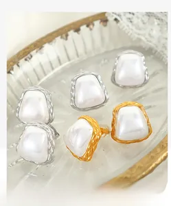 Macro shot of square pearl earrings with twisted rope metal frames in gold and silver