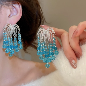 Close-up of sparkling light blue crystal beaded tassel earrings worn on ear for elegant look
