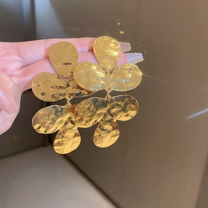 Detailed view of large gold layered petal earrings with hammered metal texture