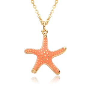 Macro detail of gold starfish pendant with orange enamel and gold bead accents