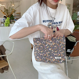 Vue rapprochée d'une pochette en velours côtelé violet à fleurs tenue par un modèle