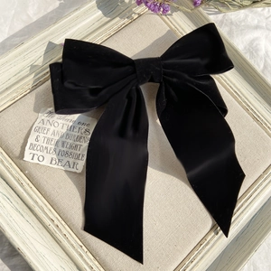Close-up of large black velvet hair bow with long ribbons on vintage frame