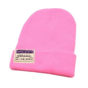 Macro shot of bright pink ribbed knit beanie with boarding pass style embroidery patch