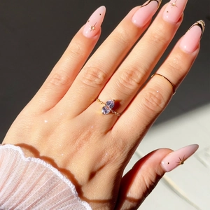 Detail of adjustable gold chain ring featuring two pear-cut purple zircon stones