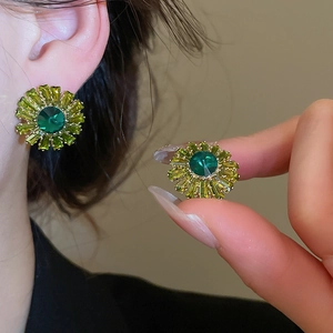 Close-up of emerald green zircon flower stud earrings with shimmering rectangular facets.