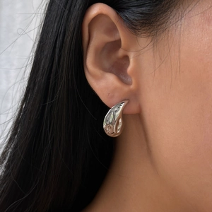 Polished silver teardrop earrings in vintage stainless steel worn by a model