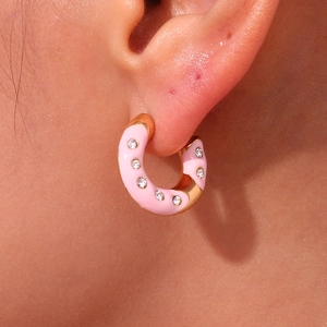 Close-up of pink enamel hoop earring with sparkling white crystals on model