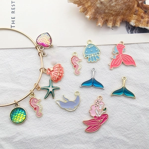 Detail of colorful ocean themed alloy charms like mermaids and starfish on a gold bracelet