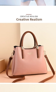 Close-up of pink tote bag with brown handles and Fashion Queen gold logo detail